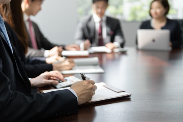 会議室の机で日本人のビジネスパーソン4人が書類とノートパソコンを前に打ち合わせをしている写真。語学力不問の求人は日本人や日系企業を相手にする仕事が中心であることを表している