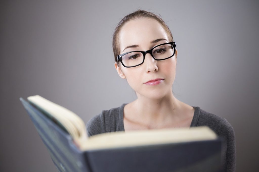 音読の章の写真。眼鏡をかけた女性が両手で本を開いて読んでいる